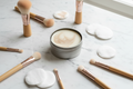 Round handmade makeup brush cleansing soap in a shallow tin can with clean and used makeup brushes
